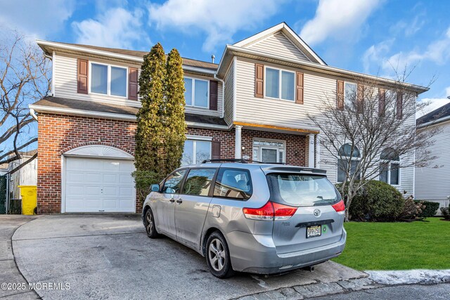 view of front of house featuring an attached garage, brick siding, driveway, and a front yard