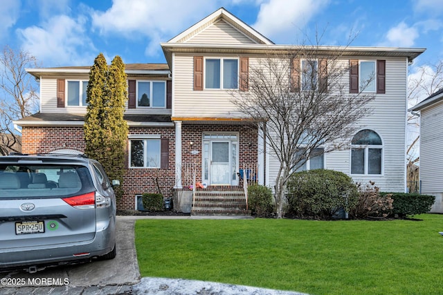 townhome / multi-family property with brick siding and a front lawn