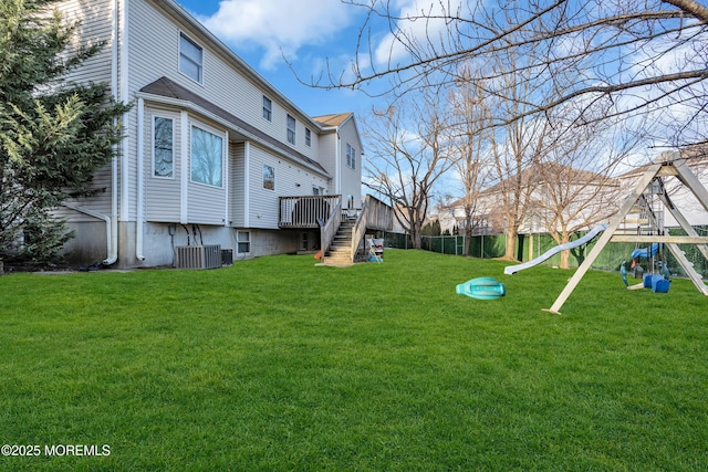 exterior space featuring fence, stairs, a deck, a lawn, and a playground