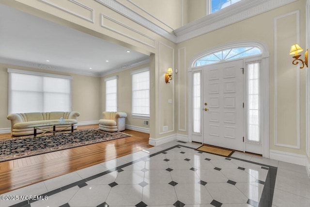 tiled entryway with crown molding and a towering ceiling