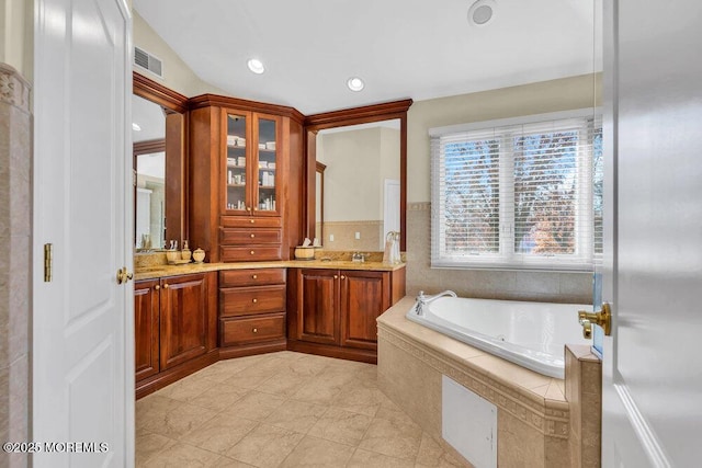 bathroom with a relaxing tiled tub and vanity