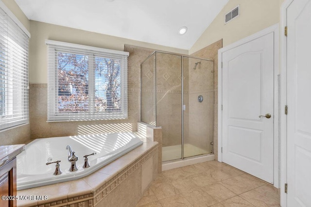 bathroom with plenty of natural light, shower with separate bathtub, and vaulted ceiling