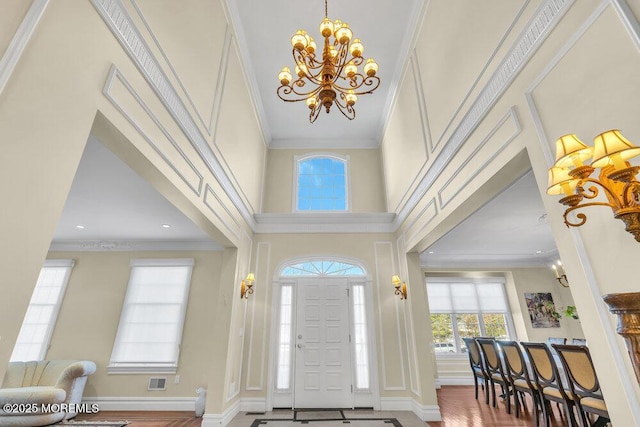 foyer featuring ornamental molding, a towering ceiling, and an inviting chandelier