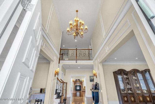 entryway with ornamental molding, a towering ceiling, and a notable chandelier