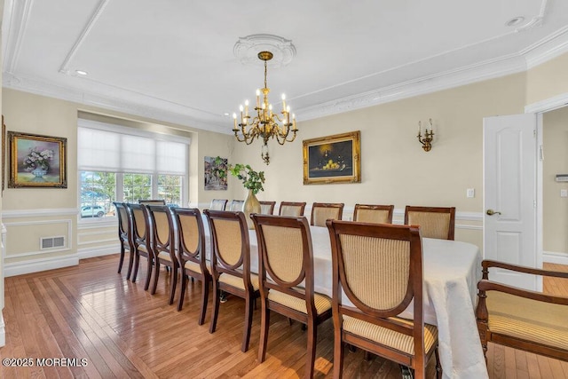 dining area featuring hardwood / wood-style flooring, crown molding, and a chandelier