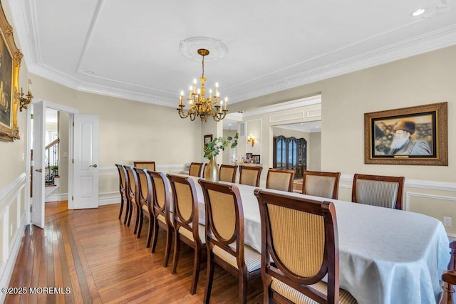 dining room with hardwood / wood-style floors, crown molding, and a notable chandelier