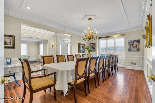 dining space featuring an inviting chandelier, hardwood / wood-style floors, and crown molding