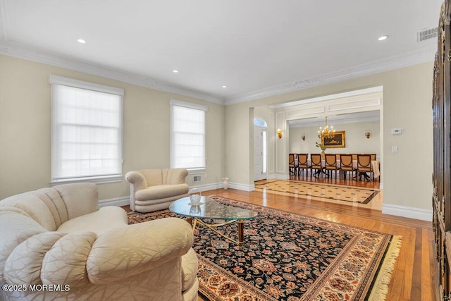 living room featuring hardwood / wood-style flooring, ornamental molding, and an inviting chandelier