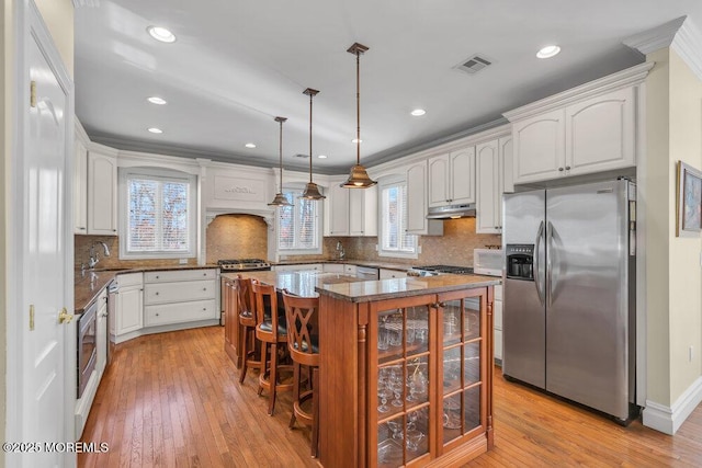 kitchen featuring stainless steel fridge with ice dispenser, a kitchen island, stone counters, pendant lighting, and white cabinets