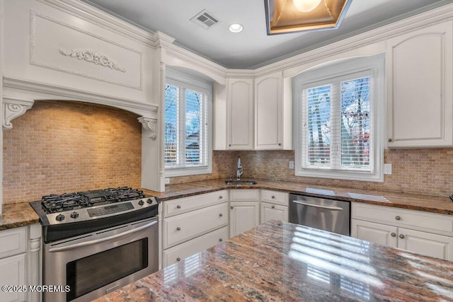 kitchen with white cabinetry, stainless steel appliances, sink, and dark stone countertops