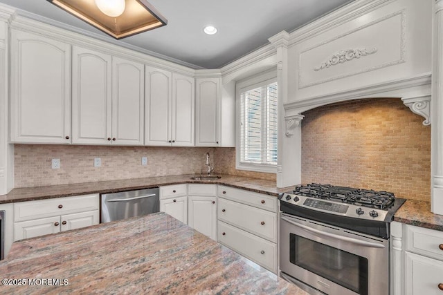 kitchen with sink, stainless steel appliances, dark stone counters, and white cabinets