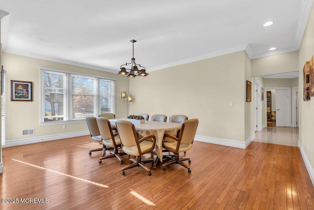 dining area featuring crown molding, light hardwood / wood-style flooring, and a notable chandelier