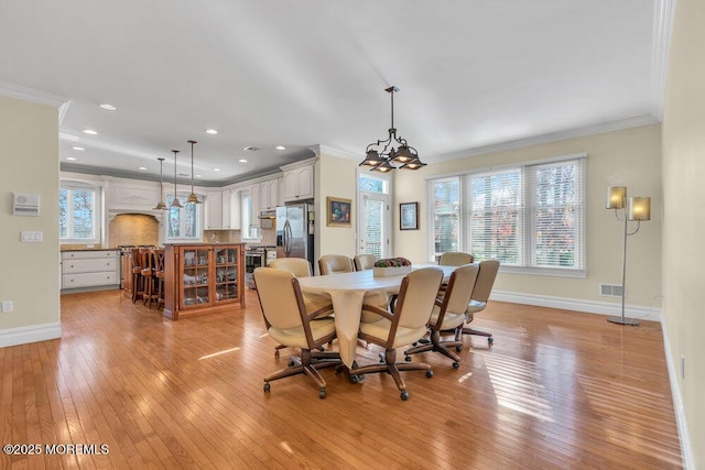 dining room with crown molding, a wealth of natural light, and light hardwood / wood-style floors