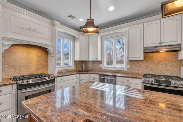 kitchen featuring white cabinets, backsplash, hanging light fixtures, stainless steel appliances, and light stone countertops