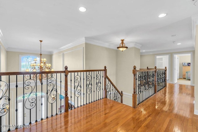 corridor with ornamental molding, a chandelier, and hardwood / wood-style floors