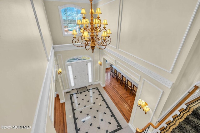 entrance foyer featuring a towering ceiling, light tile patterned floors, and a chandelier