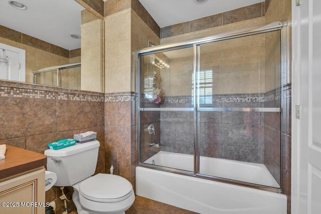 full bathroom with tile patterned floors, toilet, combined bath / shower with glass door, tile walls, and vanity