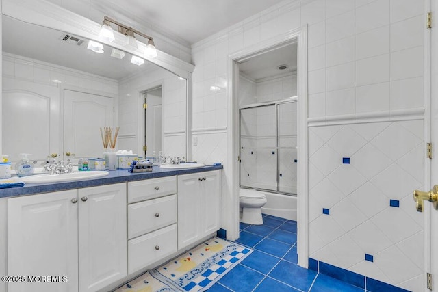 full bathroom with tile patterned floors, shower / bath combination with glass door, tile walls, ornamental molding, and vanity