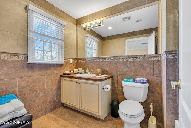 bathroom featuring tile walls, vanity, tile patterned flooring, and toilet