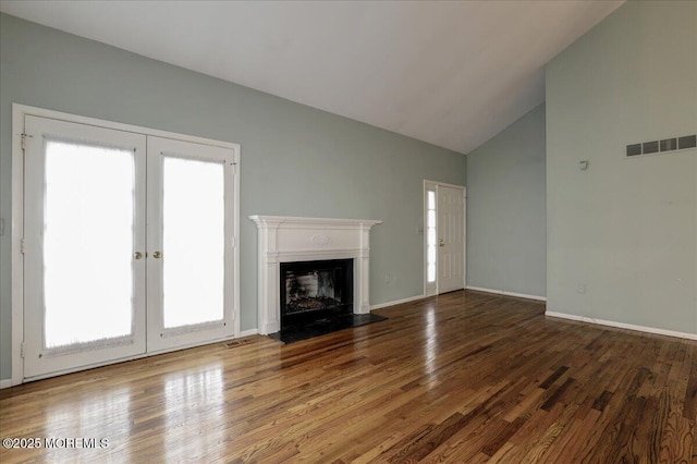 unfurnished living room featuring wood-type flooring, high vaulted ceiling, and french doors