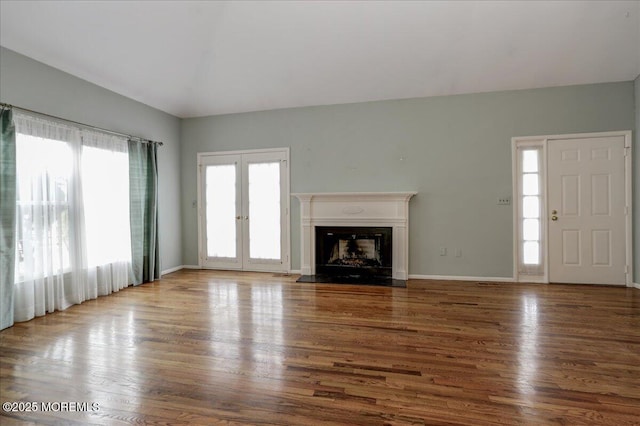 unfurnished living room with hardwood / wood-style floors, plenty of natural light, and french doors