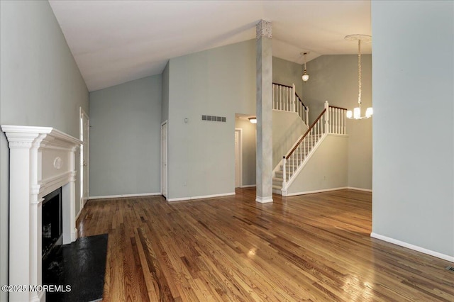 unfurnished living room with hardwood / wood-style flooring, high vaulted ceiling, and an inviting chandelier