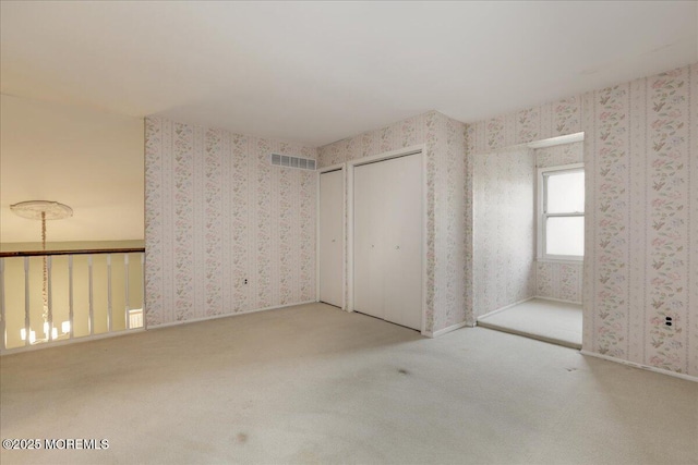 unfurnished bedroom with carpet flooring and two closets