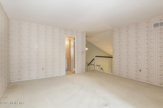carpeted empty room with vaulted ceiling
