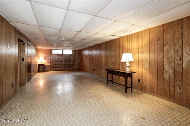 basement with a paneled ceiling and wooden walls