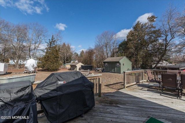 wooden terrace featuring a shed and a grill