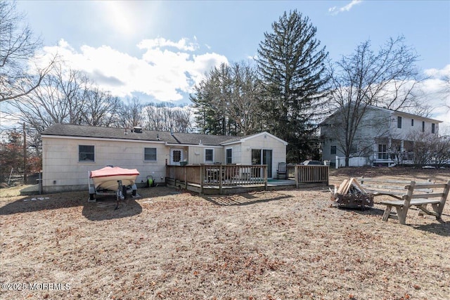 rear view of house with a wooden deck and an outdoor fire pit