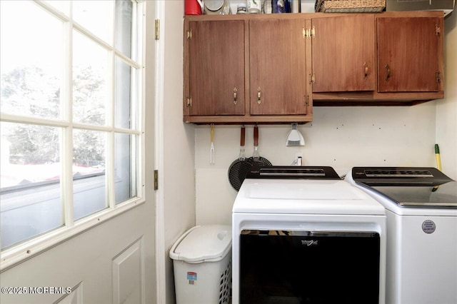 clothes washing area featuring washer and dryer and cabinets