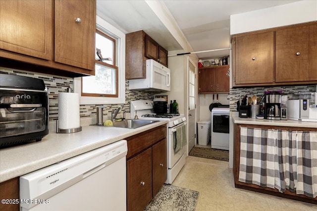 kitchen featuring white appliances, washer / dryer, sink, and backsplash