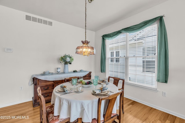 dining area featuring baseboards, visible vents, and light wood finished floors