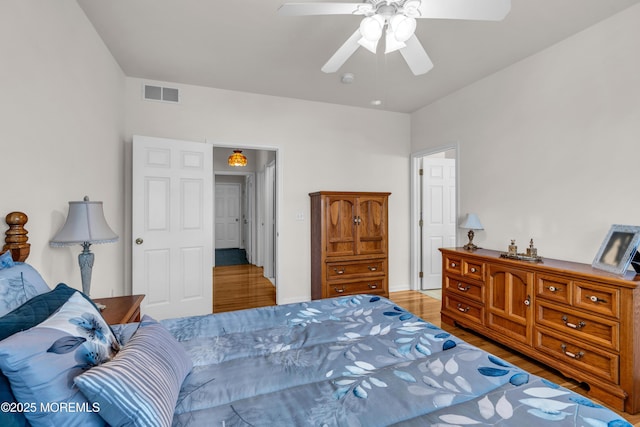 bedroom featuring a ceiling fan, visible vents, and wood finished floors