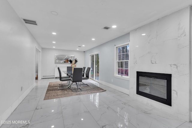 unfurnished dining area featuring a high end fireplace and baseboard heating