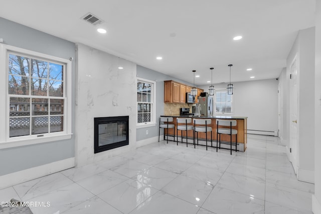 kitchen with a breakfast bar area, kitchen peninsula, a baseboard radiator, and appliances with stainless steel finishes