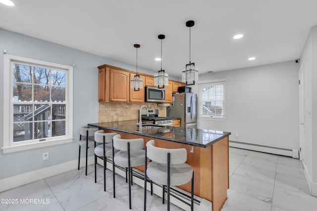 kitchen with baseboard heating, backsplash, stainless steel appliances, decorative light fixtures, and kitchen peninsula