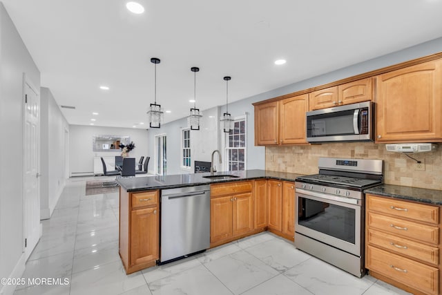 kitchen with sink, appliances with stainless steel finishes, kitchen peninsula, pendant lighting, and dark stone counters