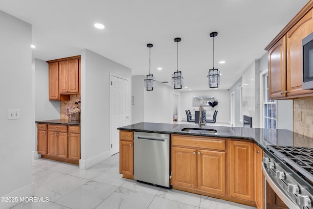 kitchen with sink, dark stone countertops, backsplash, stainless steel appliances, and decorative light fixtures