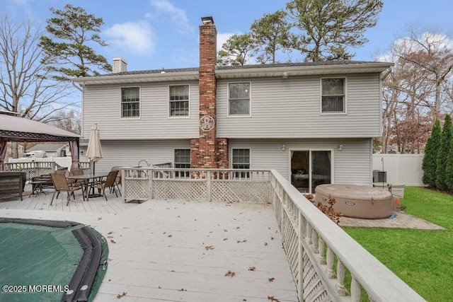 rear view of property with a hot tub, a gazebo, and a deck