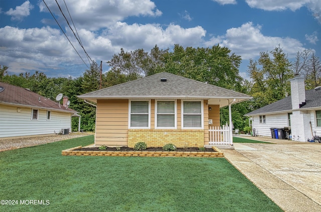 bungalow with a front yard and central air condition unit