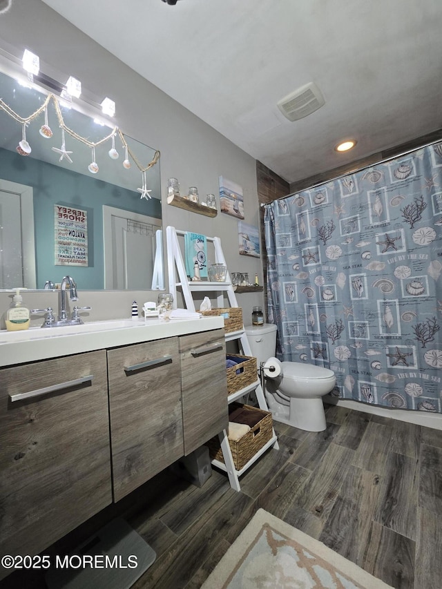 bathroom featuring hardwood / wood-style flooring, vanity, toilet, and walk in shower