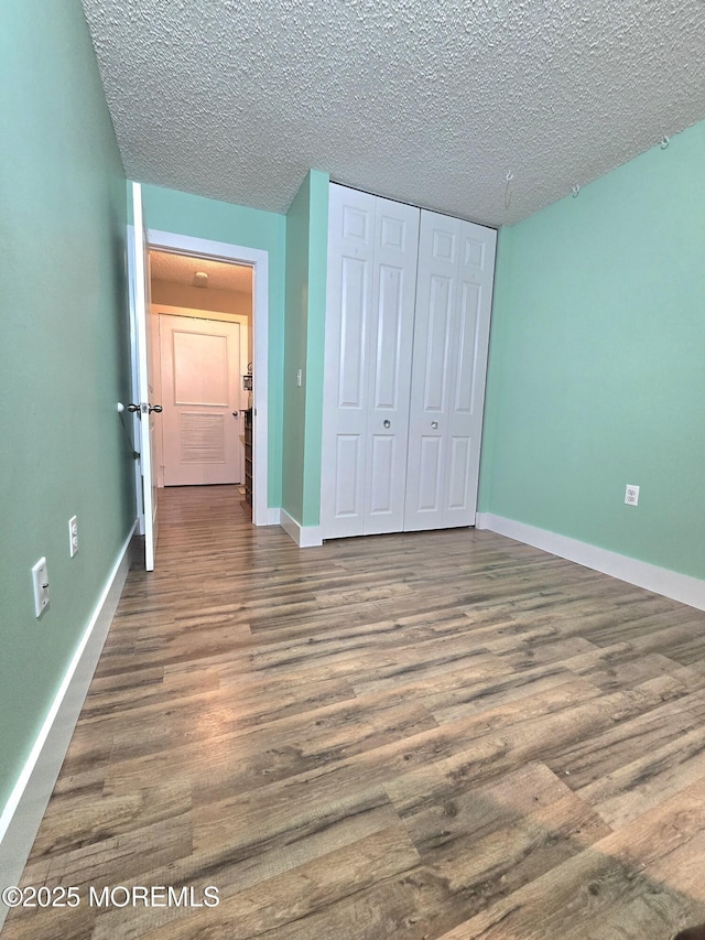 unfurnished bedroom featuring hardwood / wood-style flooring, a closet, and a textured ceiling