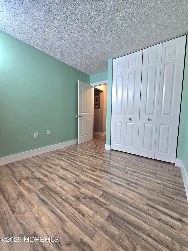 unfurnished bedroom featuring hardwood / wood-style flooring, a textured ceiling, and a closet