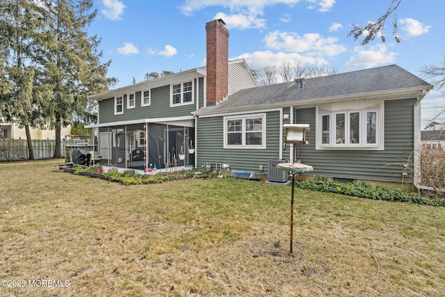 rear view of house with central AC unit, a yard, and a sunroom