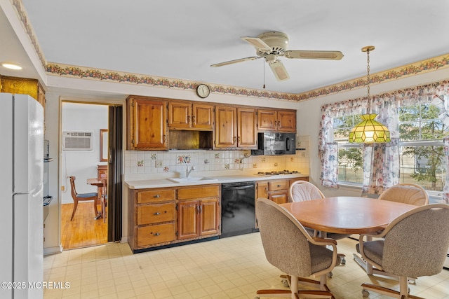 kitchen with a wall mounted air conditioner, pendant lighting, sink, decorative backsplash, and black appliances