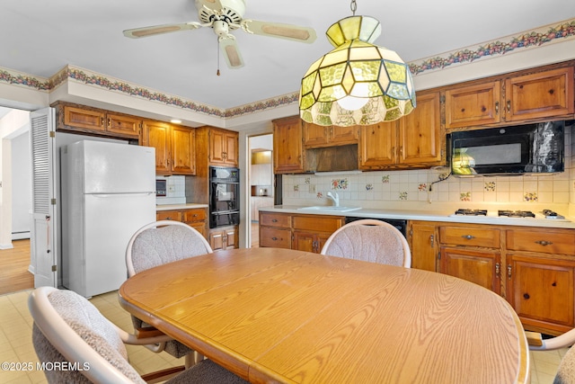 kitchen with sink, tasteful backsplash, decorative light fixtures, ceiling fan, and black appliances