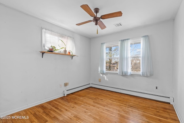 spare room featuring ceiling fan, light hardwood / wood-style floors, and a baseboard heating unit