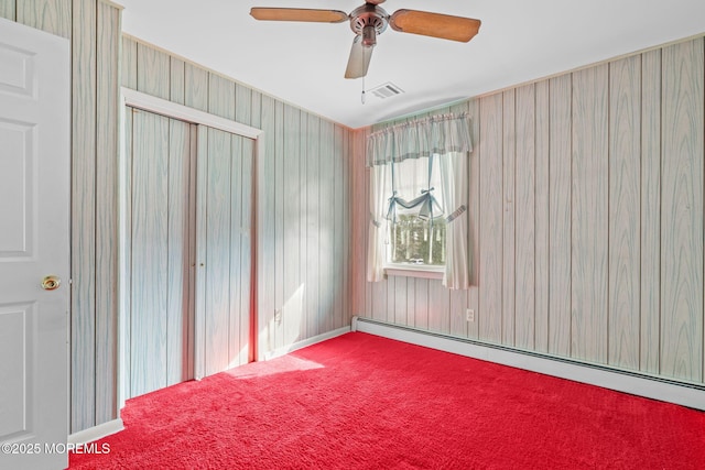 carpeted empty room with a baseboard heating unit and ceiling fan